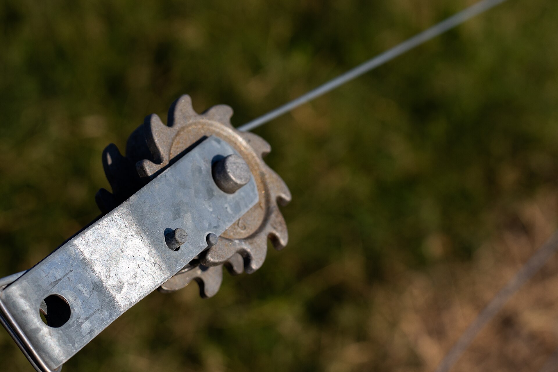 In-line ratchet strainer tensioning a smooth high-tensile fence wire