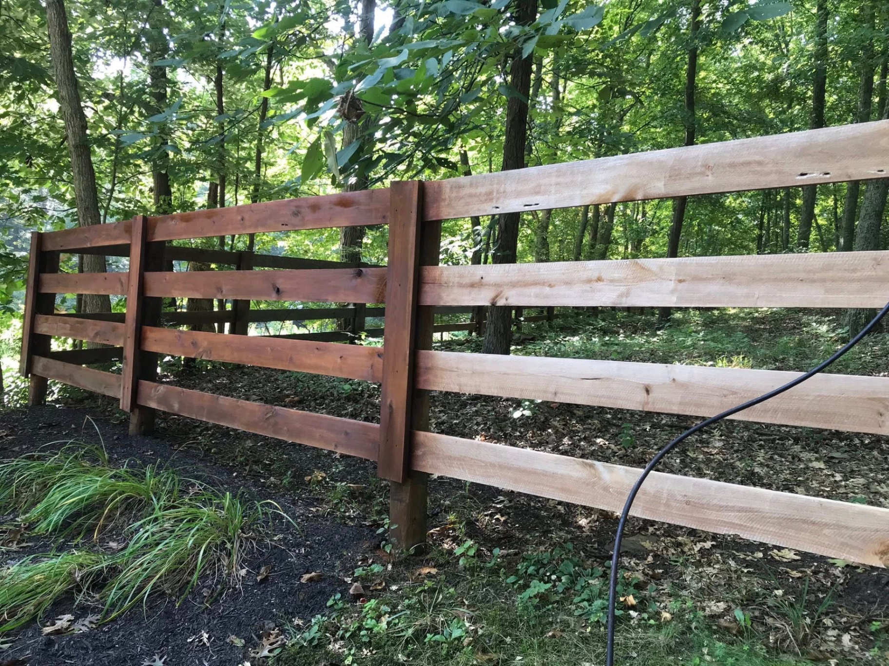 Cedar-stained board fence in wooded backyard — S&S Fencing painting project, Kentucky