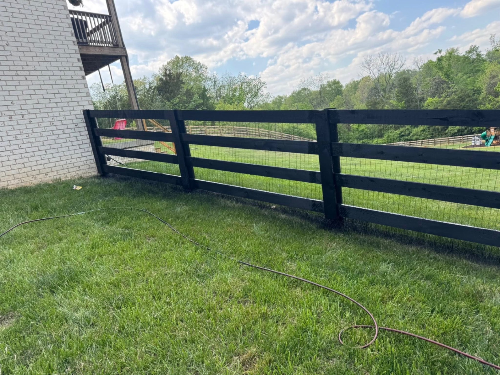 Black-stained four-board wood fence with wire mesh — S&S Fencing painting project, Kentucky