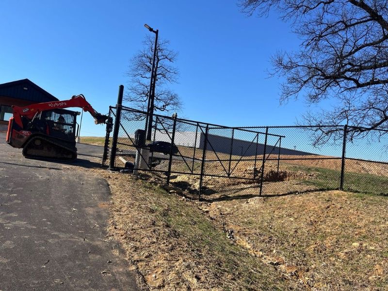 Skid loader installing commercial chain link fence posts at Four Roses